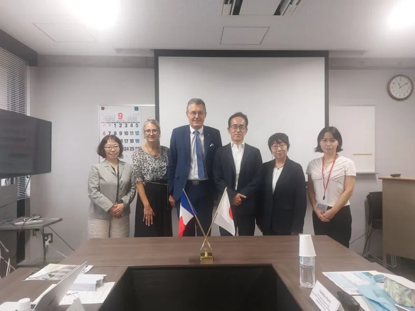 Réunion officielle entre la délégation de Mines Saint-Étienne et des partenaires japonais, avec les drapeaux de la France et du Japon posés sur une table.